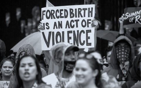 Abortion Rights Activists in Washington DC a protestor holding a sign that says forced birth is an act of violence