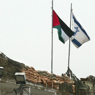 topshot a palestinian and israeli flag fly side by side at the beit jala checkpoint in the west bank 19 march 2002 israel said it had completed its withdrawal from autonomous palestinian areas in the bethlehem sector of the west bank and the north of the gaza strip, but a palestinian security official told afp that the israeli army had still not pulled out of areas in the northern gaza strip in spite of the israeli announcement afp photopatrick baz photo by patrick baz afp photo by patrick bazafp via getty images