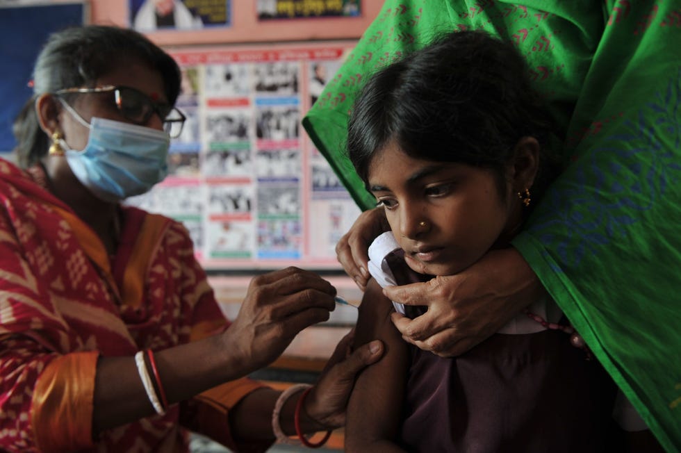 Op de basisschool Kanishail in de stad Sylhet in Bangladesh krijgt een leerling op 28 augustus 2022 een prik tegen COVID19 in het kader van een vaccinatieprogramma