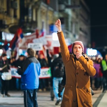 brave young man rioting downtown whistling and raising fist