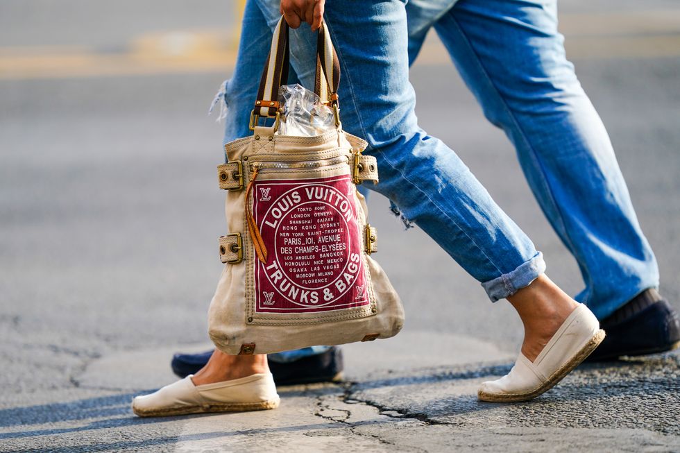 paris, france   june 03 a passerby wears cropped cuffed blue denim jeans, white flat shoes, a louis vuitton trunks  bags bag, on june 03, 2020 in paris, france photo by edward berthelotgetty images