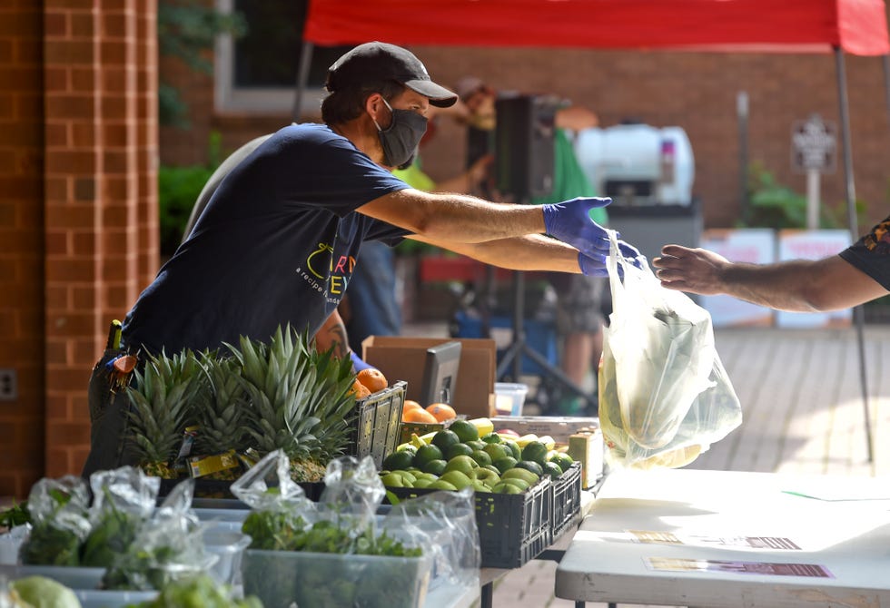 reading, pa   june 4 aaron weber, the director of operations and the farm manager for blue mountain academy hands a customer their purchases at the blue mountain academy tables in the 400 block of penn street in reading, pa thursday morning june 4, 2020 at the opening of the penn street market the farmers market opened with certain precautions against the spread of coronavirus, such as everyone wearing masks, chalk arrows on the sidewalk to indicate social distancing and which way to go photo by ben hastymedianews groupreading eagle via getty images
