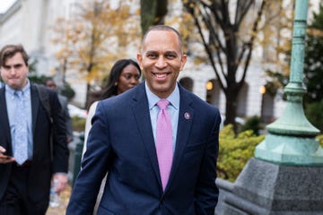 a man in a suit jacket and tie smile at the camera as he walks outside
