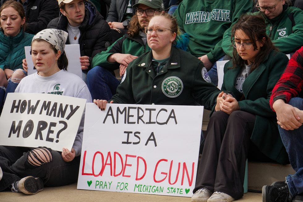 michigan state students protest holding signs that say america is a loaded gun