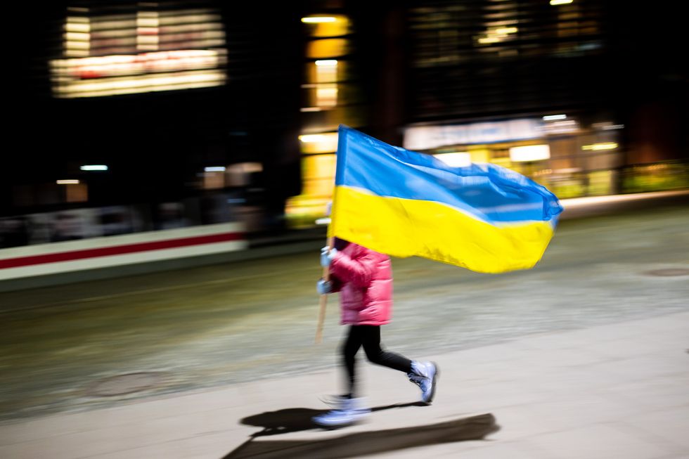 a child holding a ukrainian flag at the solidarity square during a rally regarding the anniversary of russian's invasion on ukraine