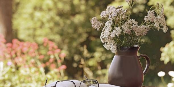 vase with wild flowers achillea, book and glasses on the table