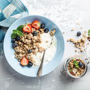overhead schoot of granola with nuts mix, yogurt, fresh berries and honey on blue plate voor healthy breakfast, top view, copy space