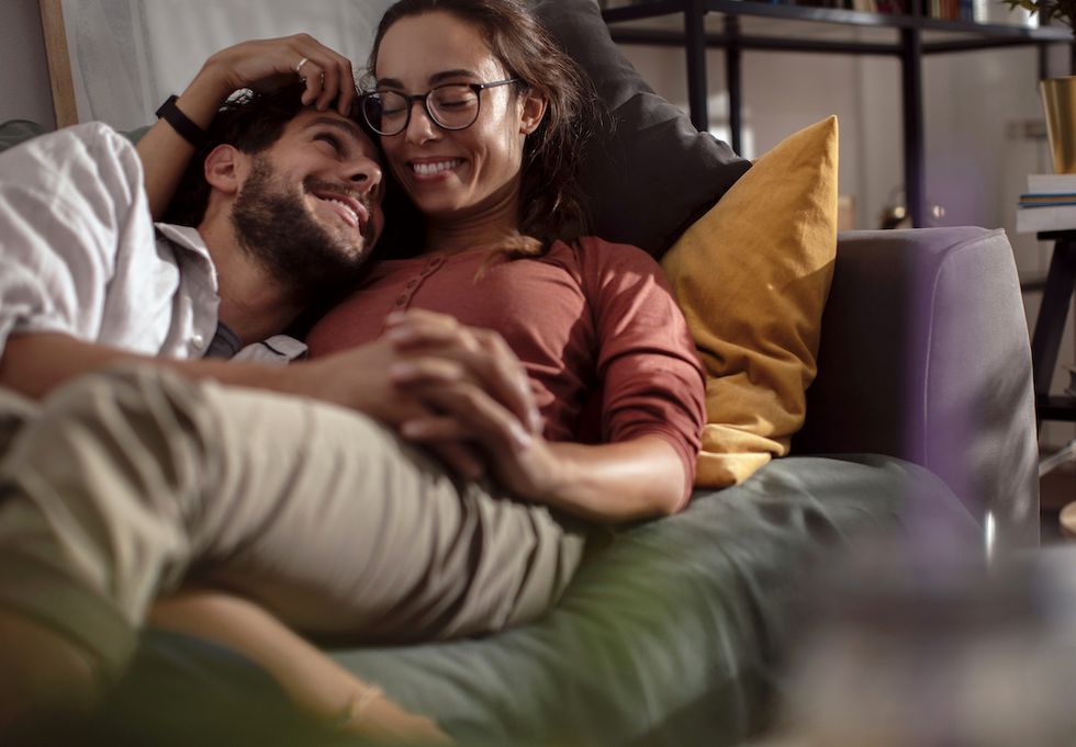 young smiling couple holding hands and relaxing on their living room couch