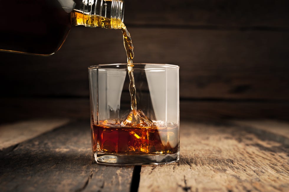 pouring glass of whiskey, close up whisky on the rocks