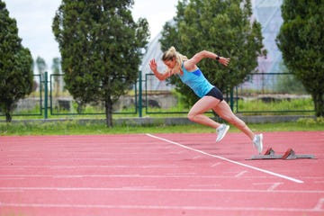 track athlete exploding out of the starting blocks in stadium