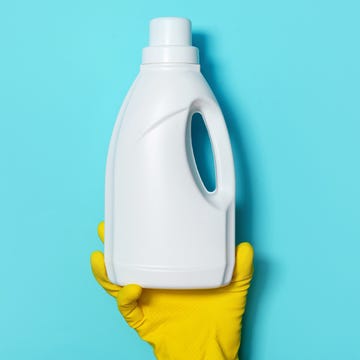 Hand in glove holding white plastic bottle of cleaning product, household chemicals. Copy space. Cleaning service concept. Household chemical cleaning products, brushes and supplies. Detergent bottle hand in glove holding white plastic bottle of cleaning product, household chemicals. copy space. cleaning service concept. household chemical cleaning products, brushes and supplies. detergent bottle.