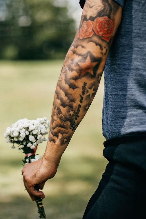 young tattooed man holding a flower bouquet