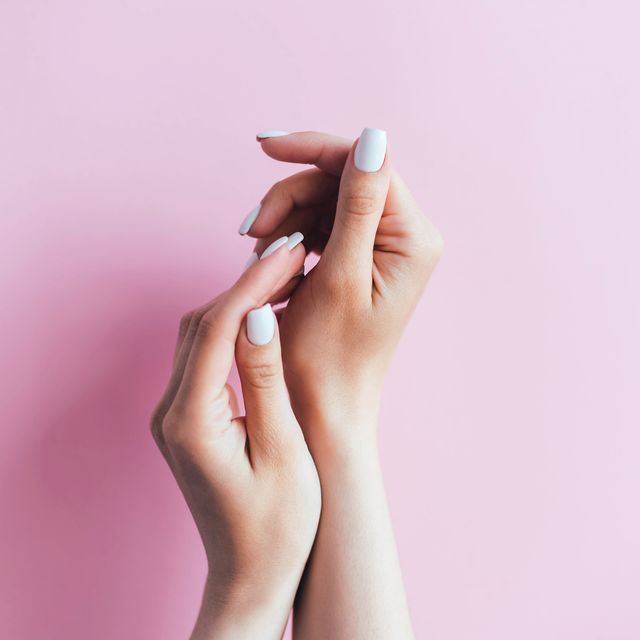 female hands with white manicure on a pink background manicurist salon manicure