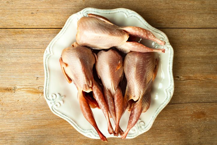 quails plucked raw fresh ready for cooking on white plate on rustic wooden background close up top view selective soft focus shallow depth of field text copy space
