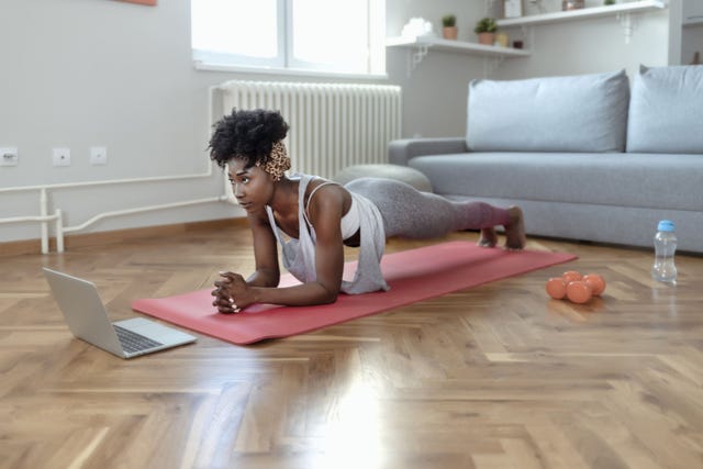 woman performing a plank exercise on a yoga mat in a home workout setting