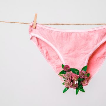 pink womens underwear decorated with flowers on clothesline isolated on white, concept photography for feminist blog high quality photo