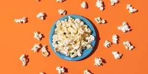 directly above view of popcorn in a blue plastic plate on orange background