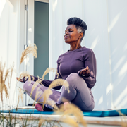 mature black woman practicing yoga on mat outside
