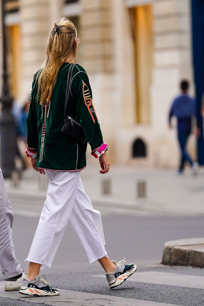 paris, france   july 04 a passerby wears white ripped denim cropped jeans, sneakers shoes, a green velvet jacket with printed geometric patterns and pink cuffs, a black leather quilted bag, on july 04, 2020 in paris, france photo by edward berthelotgetty images