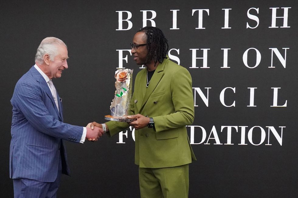 founder and creative director of labrum london foday dumbuya r receives, from britains king charles iii l, the queen elizabeth ii design award during a special industry showcase event hosted by the british fashion council bfc at 180 studios, in london, on may 18, 2023 photo by jonathan brady  pool  afp photo by jonathan bradypoolafp via getty images