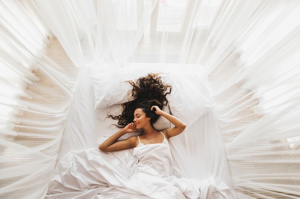 beautiful smiling girl awakening in white bed happy wake up and start new day leisure and rest view from above wellbeing concept