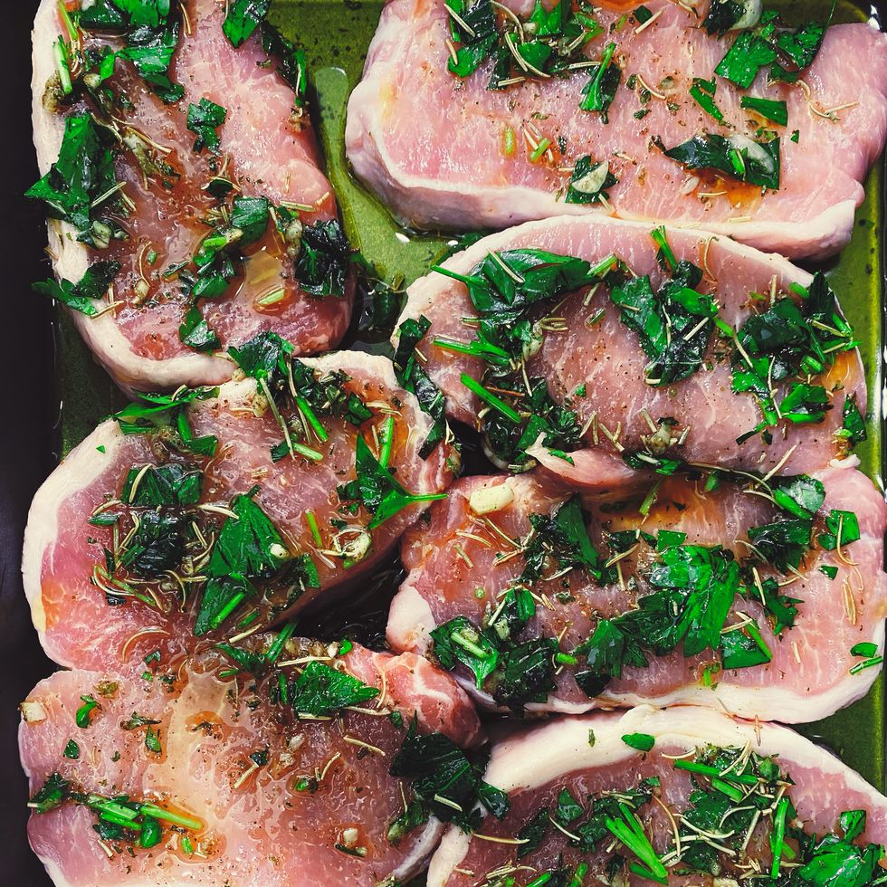 pork chops marinating with rosemary, parsley and olive oil