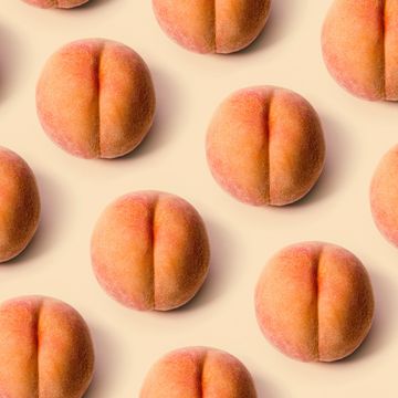 a detailed image of a freshly picked ripe peach  photographed on a peach colored background