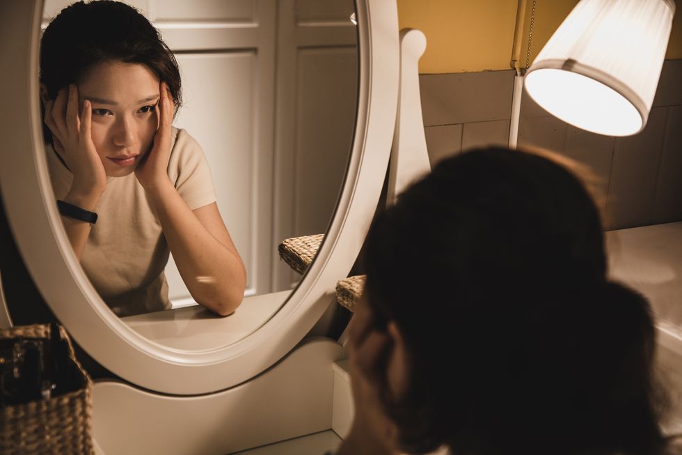 asian woman sitting in front of the dressing table feeling depressed