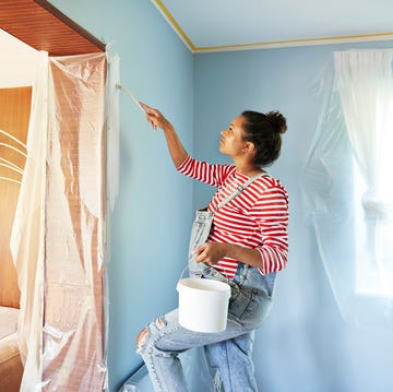 Pregnant woman in bib overalls renovating room which is the best paint for decorating my home