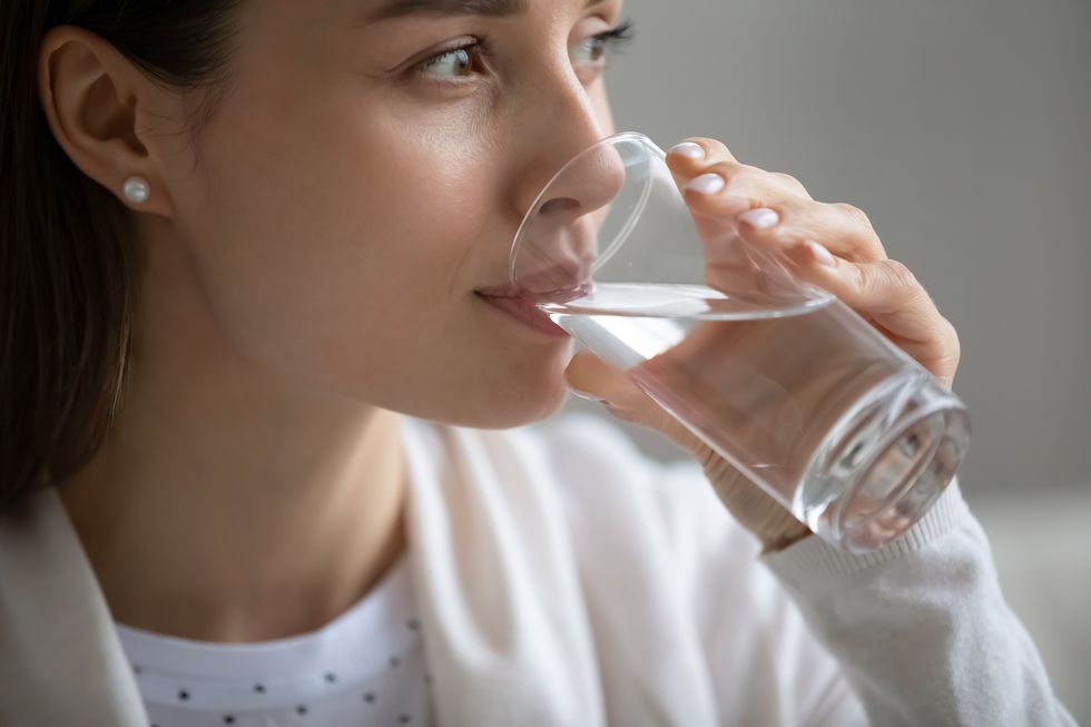side close up head shot view happy pleasant young woman enjoying drinking water indoors positive healthy thirsty girl sipping pure stilled aqua, planning day or visualizing future in morning