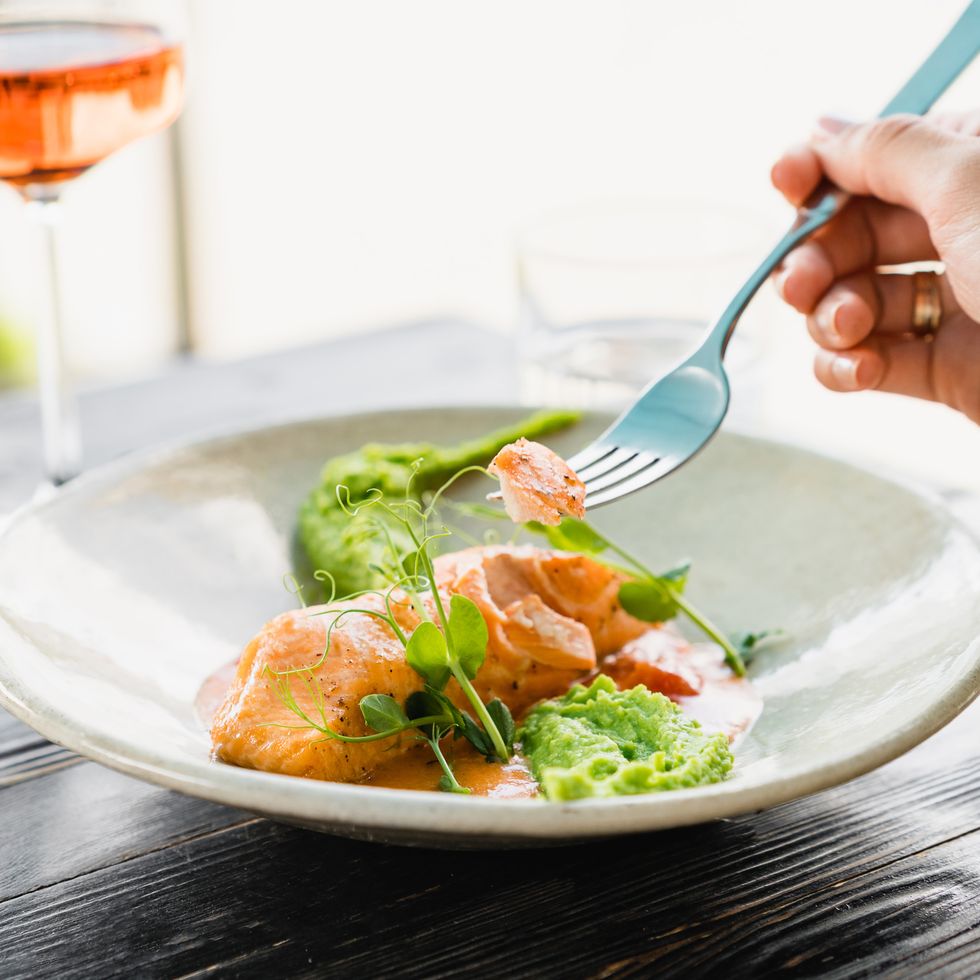 woman eating baked salmon with pea puree