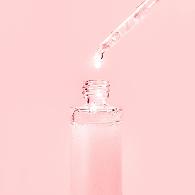 pipette with dose of fluid hyaluronic acid or beauty serum on pastel pink background cosmetics concept flat lay place for text
