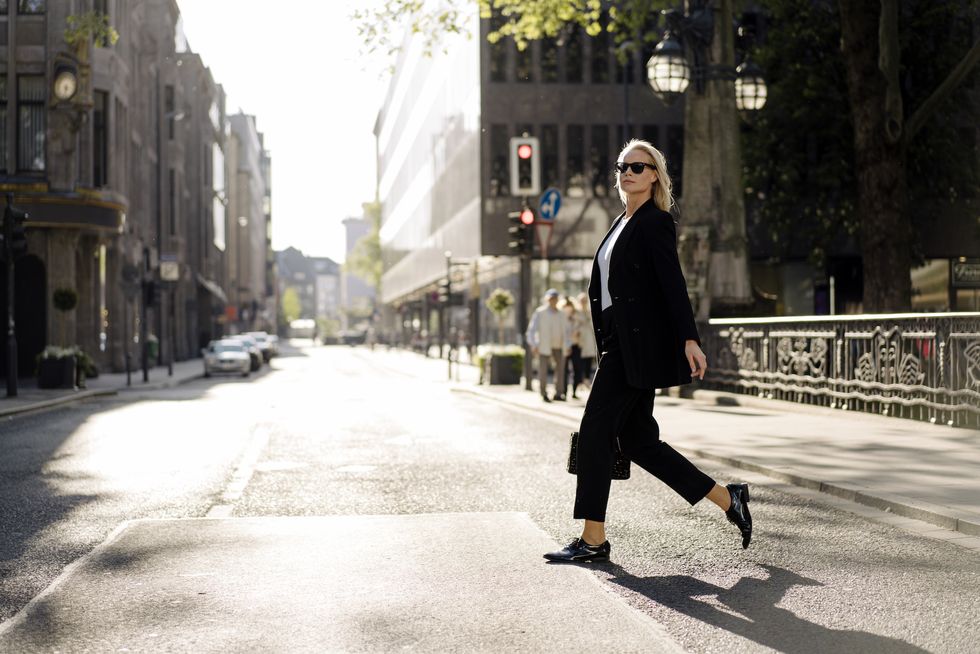 fashionable businesswoman crossing street in city