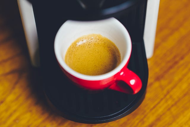 close up of a red coffee espresso cup on a nespresso machine in moody setting