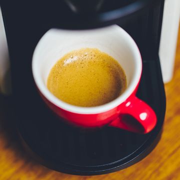 close up of a red coffee espresso cup on a nespresso machine in moody setting