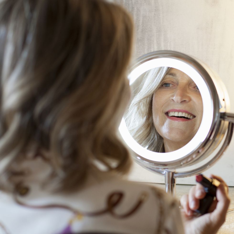 woman smiling at herself in mirror