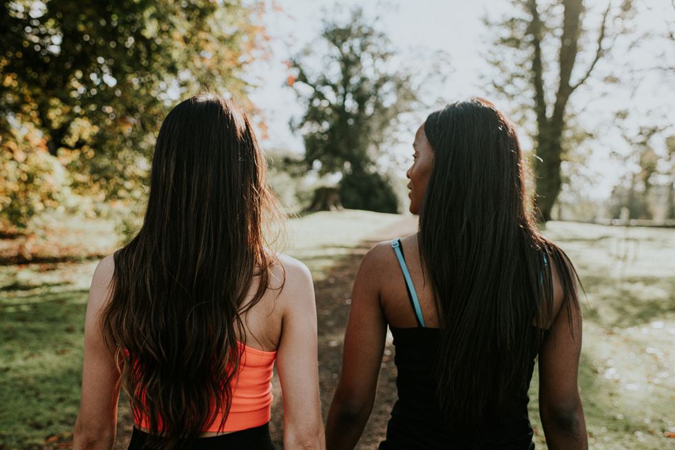 two woman walking through a sunny park together during an exercise session they are having a in depth conversation as they walk