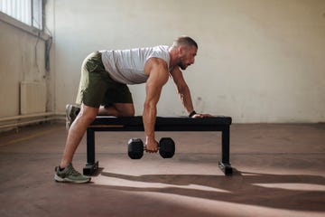 side shot of a fit caucasian man working out with dumbbells in the gym