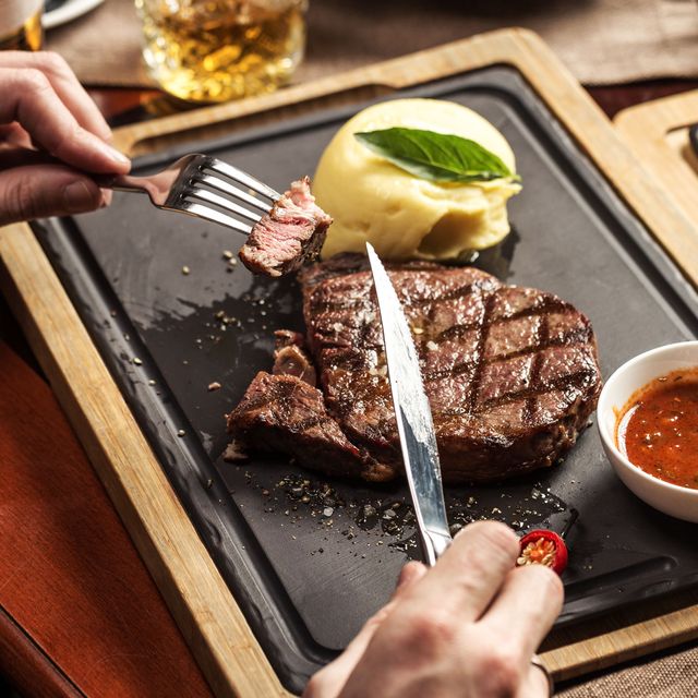 hands cutting up steak