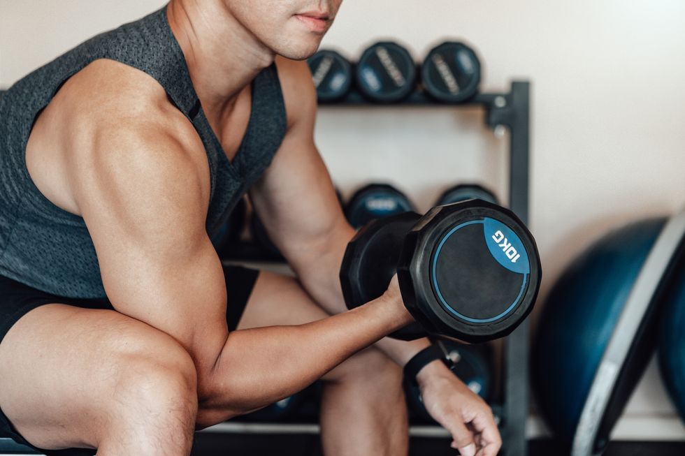 close up shot of a young man lifting dumbbell at the gym bodybuilding motivation and determination arm curls