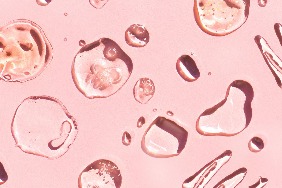 top view of blots and smears of various lotions and gels spread on pink background beauty product of the year