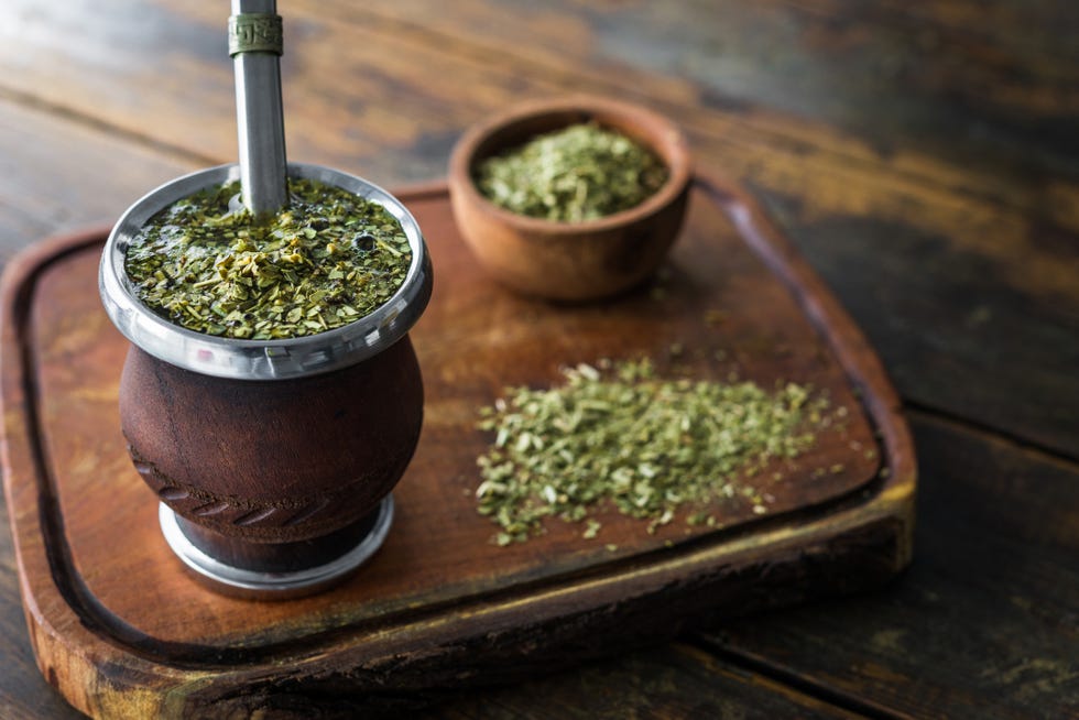 traditional argentinian yerba mate tea in a calabash gourd with bombilla stick against wooden background