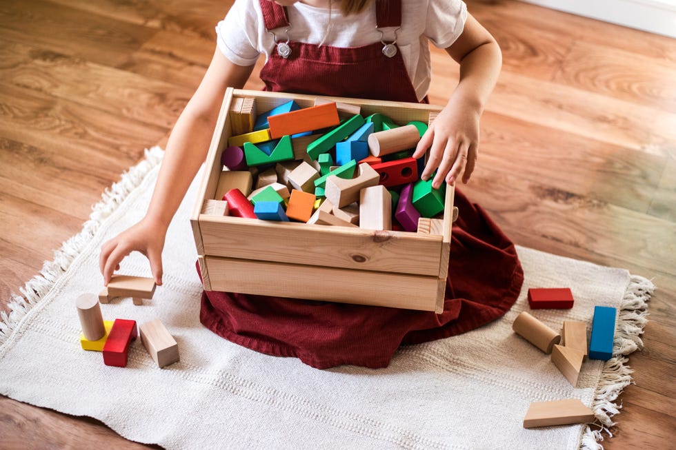 little girl cleaning up the toy box at home childs space organization