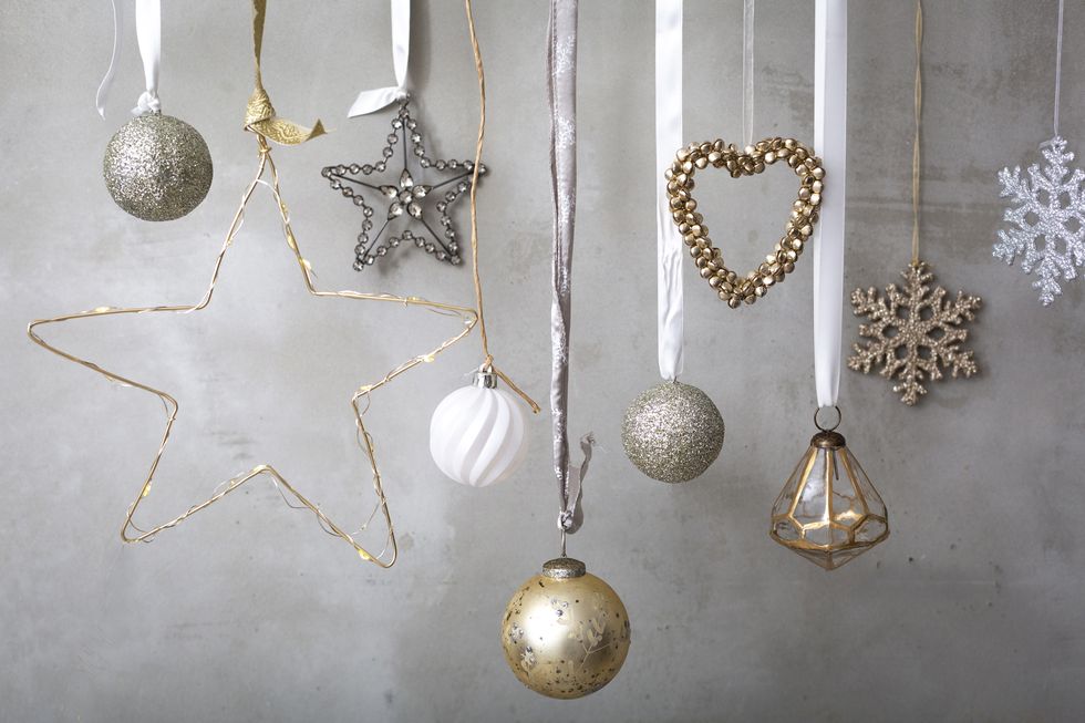 christmas decorations, silver, white and gold baubles on ribbons on grey background