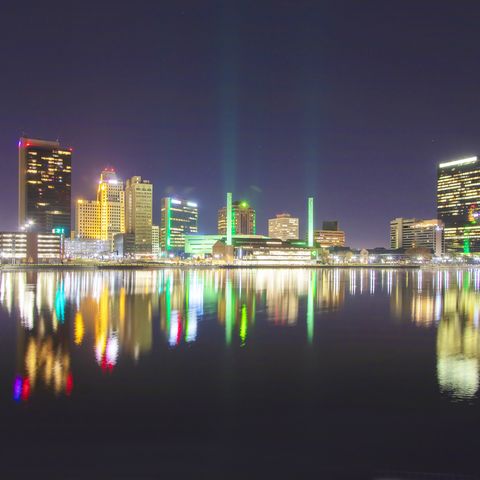 as seen in this image, toledo ohio has a colorful night presence the lights of the city are reflected on the calm surface of the maumee river, while some also project upward into the night sky