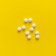white pills on yellow background medicine, medication, painkillers, tablet, medicaments, drugs, antibiotic, vitamin, treatment pharmacy theme top view on the pills scattered on the white surface