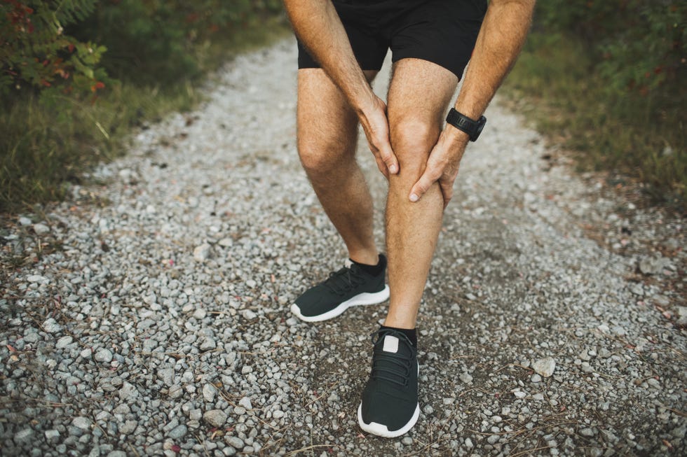 knee injury on running outdoors man holding knee by hands close up and suffering with pain sprain ligament or meniscus problem jogging and health problem accident and first aid inflammation of knee joint of runner athlete