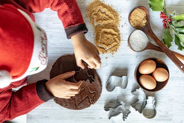 overhead view of child with santa hat using the cutter for the praparation of christmas cookies