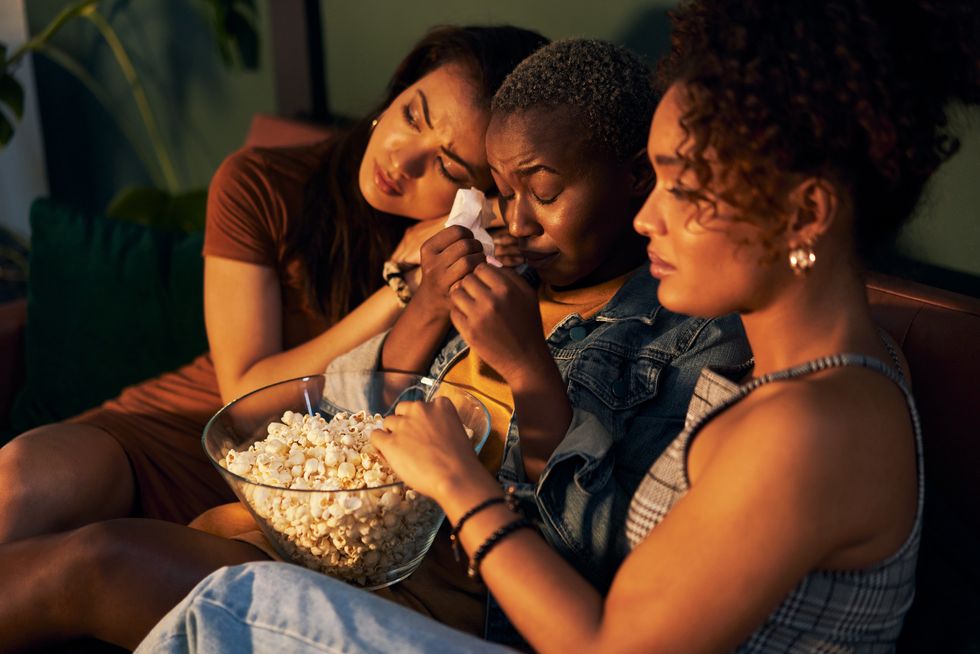 shot of three friends eating popcorn while watching something together