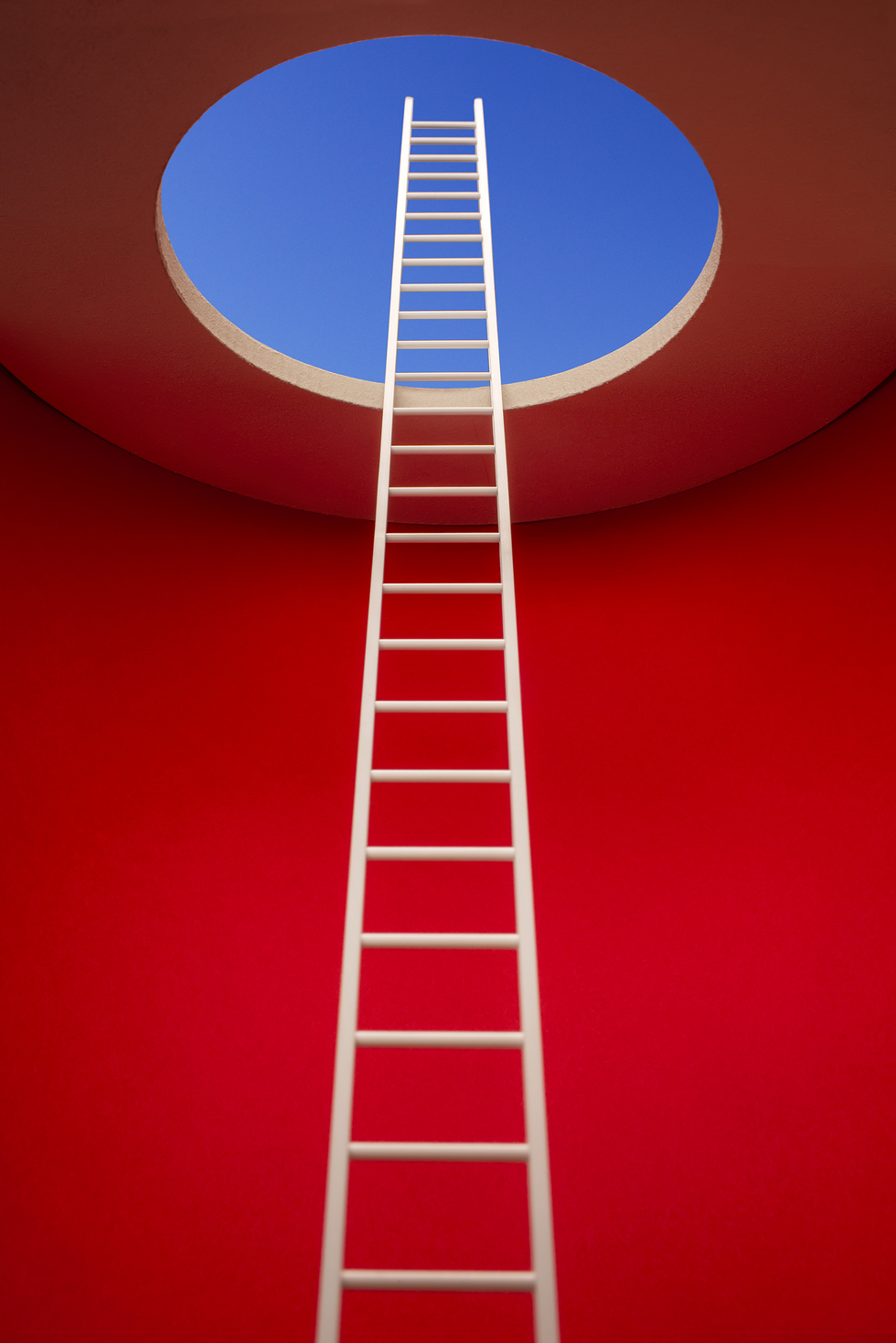 white ladder leading out of bright red room to a hole in ceiling, blue sky
